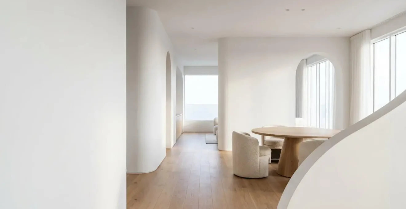 A modern minimalist living space featuring flowing curved architectural elements and soft organic shapes creating visual harmony