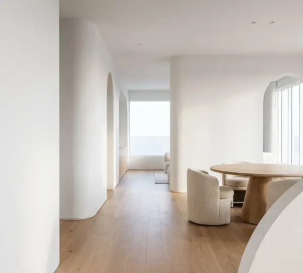 A modern minimalist living space featuring flowing curved architectural elements and soft organic shapes creating visual harmony